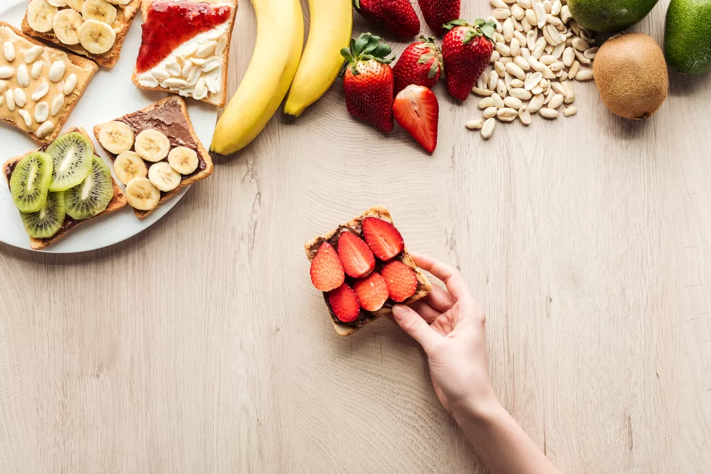 top view of woman holding fruit toast at wooden ta 2024 11 09 00 06 25 utc