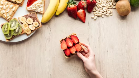 top view of woman holding fruit toast at wooden ta 2024 11 09 00 06 25 utc