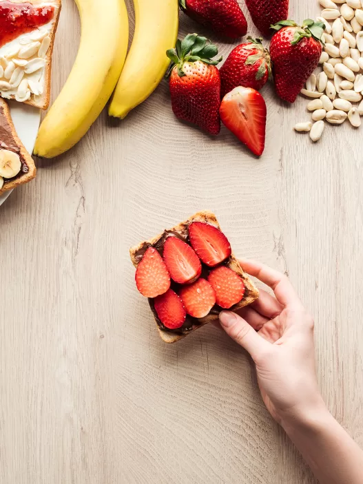 top view of woman holding fruit toast at wooden ta 2024 11 09 00 06 25 utc